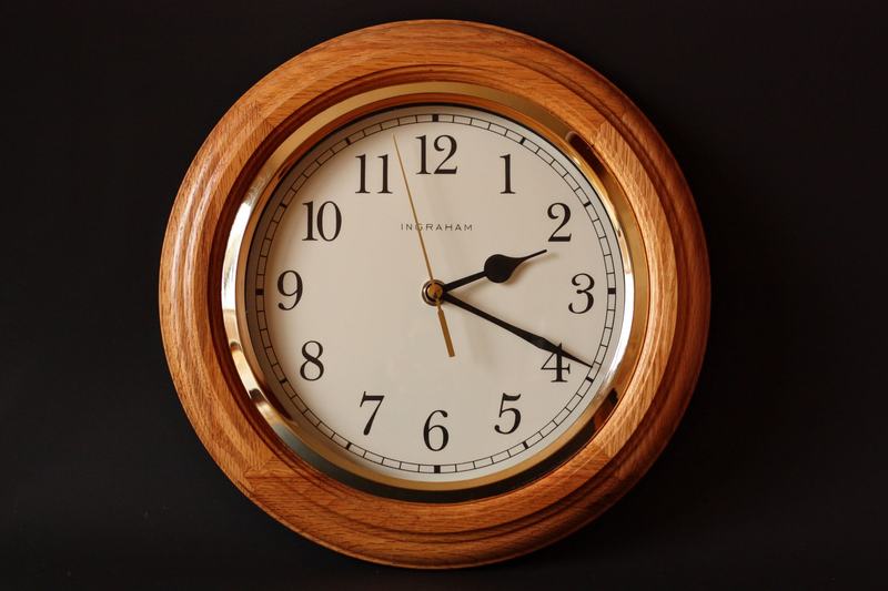 Round analog clock with a wooden frame