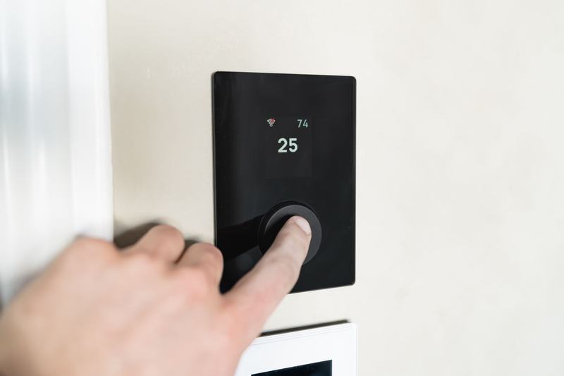 Hand touching a wall-mounted digital thermostat