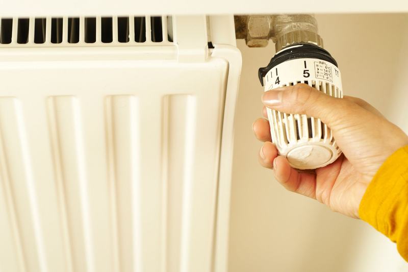 Hand turning a dial on a radiator thermostat