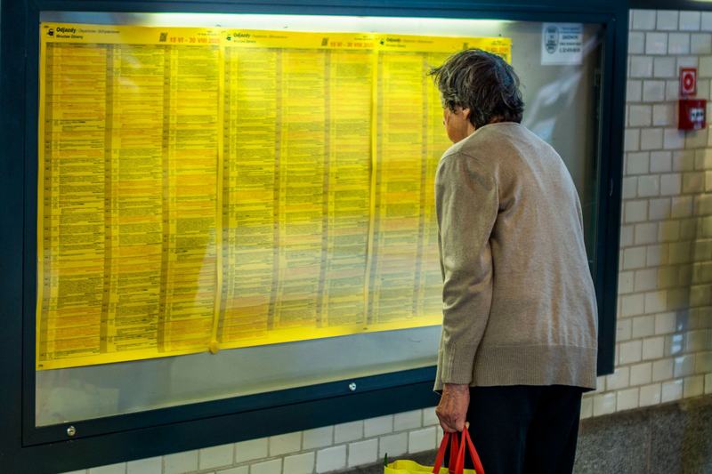Traveler reading a printed timetable at a station