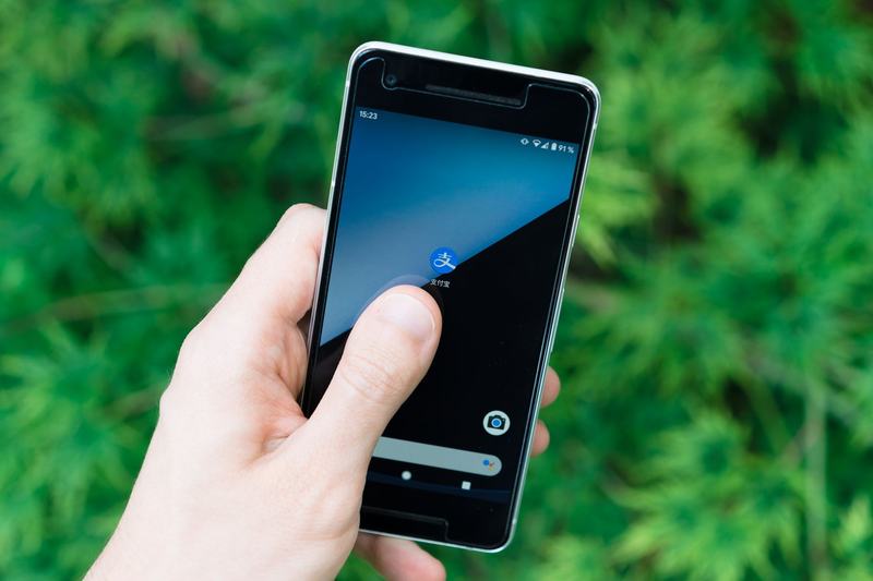Hand holding a smartphone outdoors