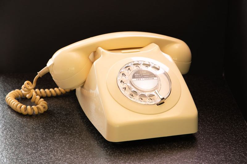 Cream-colored rotary dial telephone with a coiled cord